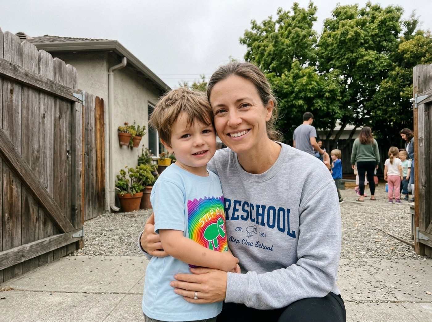 A mom in a Step One sweatshirt with her son in the rainbow alligator tee at pickup